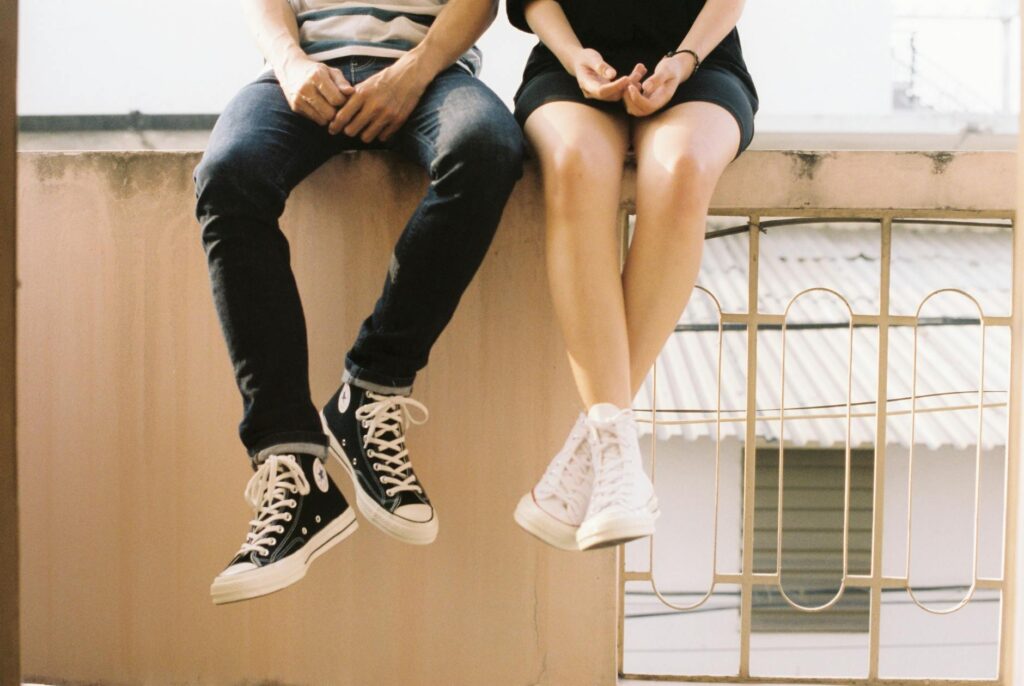 young couple sitting together, wearing Converse