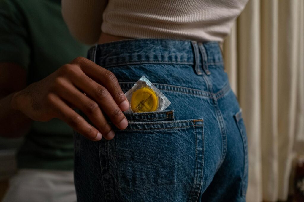 person pulling a condom out of a pocket